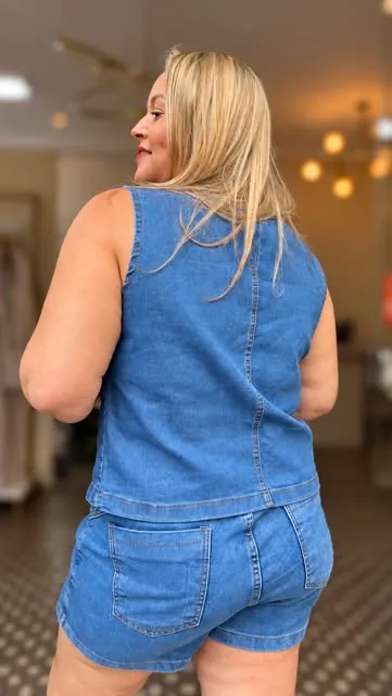 Mychelle de costas, com conjunto jeans, dentro da loja