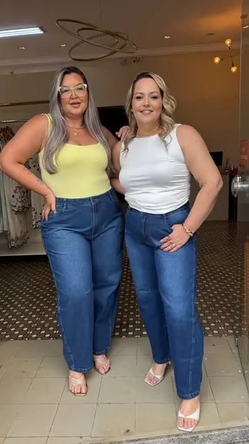 Duas mulheres de jeans e regata na entrada da Realce